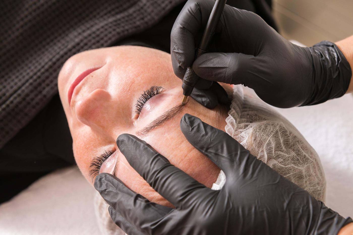 Kristina brengt met handschoenen permanente make-up aan bij een klant
